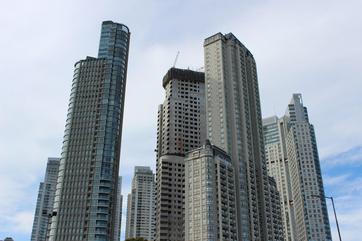 Prédio em construção ao lado de edifícios modernos, simbolizando atraso na entrega de imóvel comprado na planta.